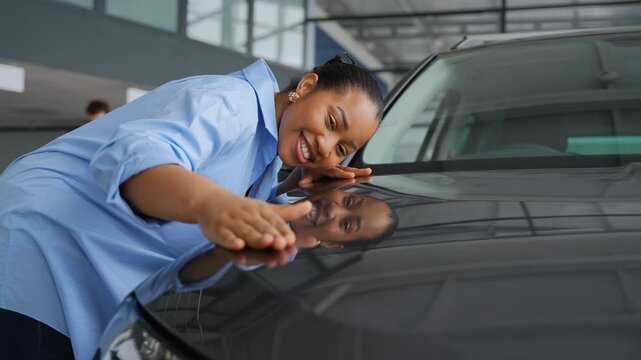 Customer caressing new car hood in dealership showroom