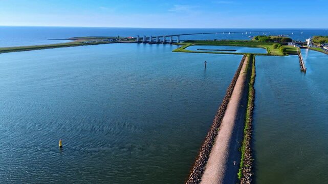 Waterscape of lake Markermeer with dikes and sluices. Multiple sailboats at on the water backdrop. Aerial view.