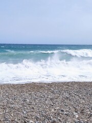 Serene Coastal Scene with Ocean Waves and Pebble Beach at Daytime