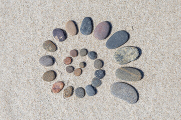 Spirale aus von gross nach klein werdenden Steinen am Strand von Børsmose, Dänemark an einem kalten Tag im April. 