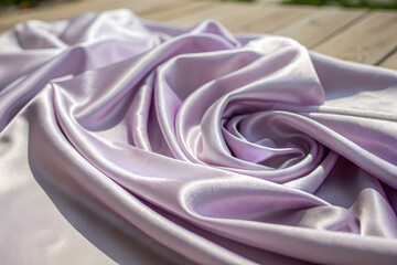 Fototapeta premium Lilac Satin Fabric with Elegant Folds and Soft Shine on Wooden Surface