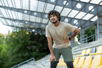 A tired jogger takes a moment of rest, experiencing side stitches after his fitness activity.