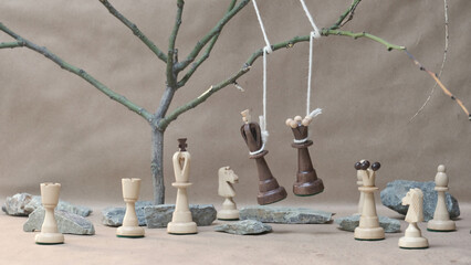 chess pieces black king and queen hanging on noose among white chess pieces