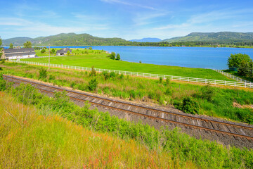 Railroad tracks pass homes and farms along the Pend Oreille River near Priest River, North Idaho at Spring.