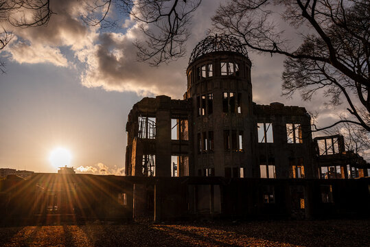 Dramatic sunset behind the The Hiroshima Peace Memorial (Genbaku Dome). Sunbeams on the horizon. Hiroshima, Japan