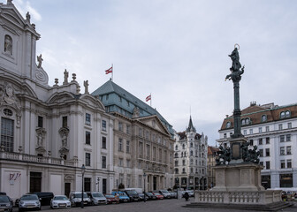 View of the Mariensule, the 17th-century plague column standing before the Kirche am Hof, its gilded Virgin Mary statue contrasting with the church's stark Gothic facade on Am Hof square.