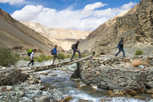 Hikers crossing a torrent on a footbridge in Zingchen gorge, Hemis National Park, Ladakh region, state of Jammu and Kashmir, India, Asia