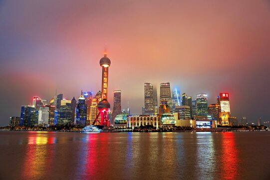 Brightly lit skyline of Lujiazui shrouded in fog at night, Shanghai, China