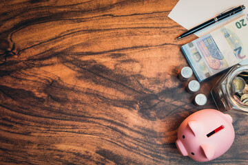 Business concept. Pink Piggy Bank on a Wooden Table Surrounded by Coins, Cash and Financial Tools...