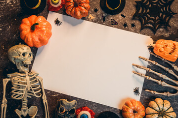 Halloween flat lay. Halloween Decoration with Pumpkins, Skeleton, Spiders, Candles, and Blank Paper...