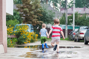 Two Young Children Running Through Rain Puddles in Summer Neighborhood