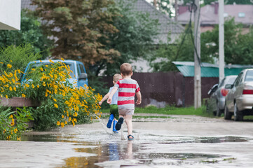 Two Young Children Running Through Rain Puddles in Summer Neighborhood