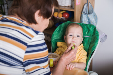 Happy Baby Being Fed by Grandmother at Home
