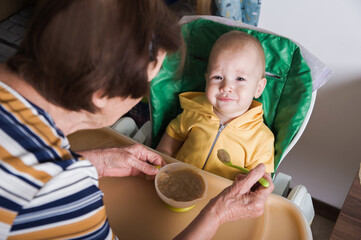 Happy Baby Being Fed by Grandmother at Home