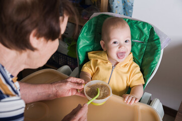 Happy Baby Being Fed by Grandmother at Home