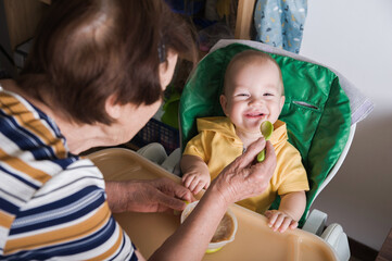 Happy Baby Being Fed by Grandmother at Home