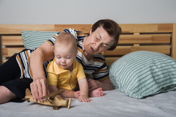 Grandmother Playing with Baby and Wooden Toy Airplane