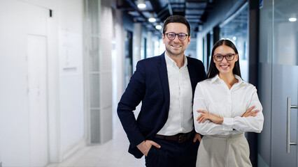 Two professional executive business team woman and man smiling at camera standing in office lobby hall. Successful company managers team portrait