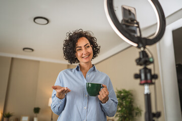 relax mature woman hold coffee and talk with public on live stream
