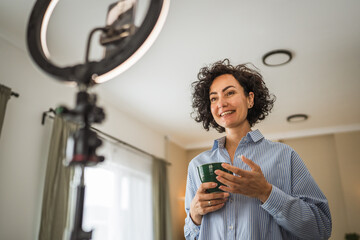 relax mature woman hold coffee and talk with public on live stream