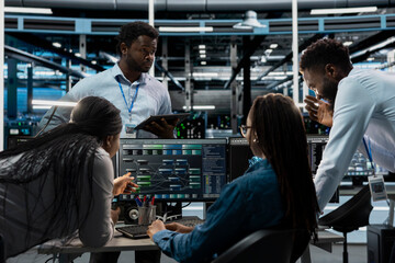 System administrators programming in AI data center housing advanced equipment used for machine...