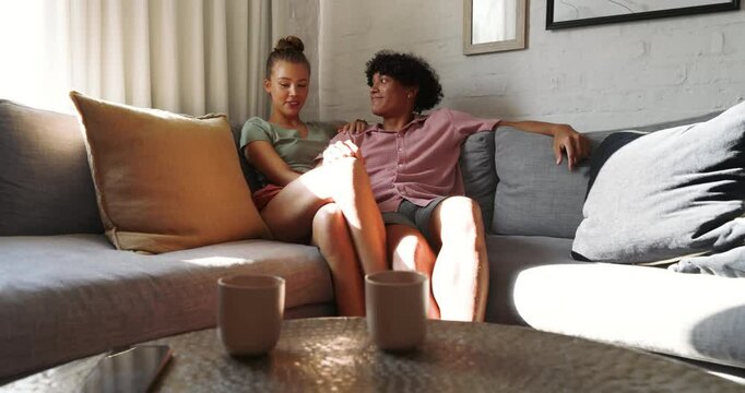 Relaxing on sofa, young diverse couple enjoying quality time together at home