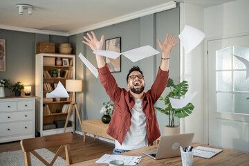Happy architect throwing papers in the air celebrating success working from home