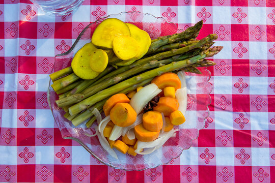 Pickled vegetables on a glass plate with a checkered picnic table cloth 