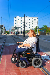 Happy woman using electric wheelchair waiting at tram station