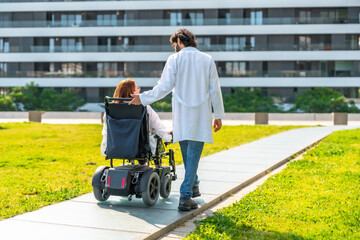 Doctor pushing patient in wheelchair in modern hospital garden