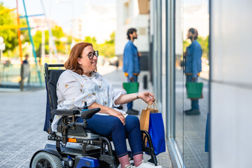 Happy woman in wheelchair doing shopping in a modern city