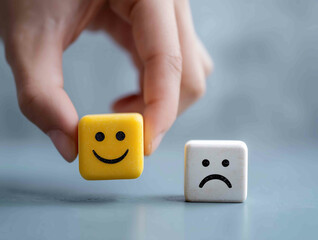 Hand holding smiley happy face on white cube and unhappy sad emotion on the floor World Mental Health Day Feedback rating Customer service review Think posi