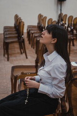 Naklejka premium Woman Immersed In The Prayer At The Church With A Rosary 