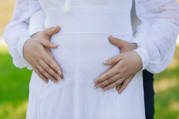 Tender hands gently cradling a pregnant belly, showcasing love, anticipation, and the joy of...
