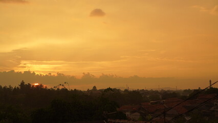 Golden Sunset Over a City with Silhouetted Trees and Rooftops