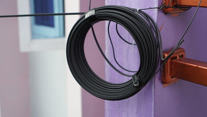Coiled black cable attached to a purple wall with brown metal supports