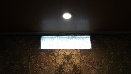 Basement window with floral wallpaper and overhead light fixture