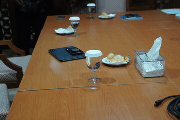 Meeting Table Setup with Water Glasses, Snacks, and Electronic Devices