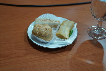 Assorted Indonesian pastries on a plate, with a glass of water