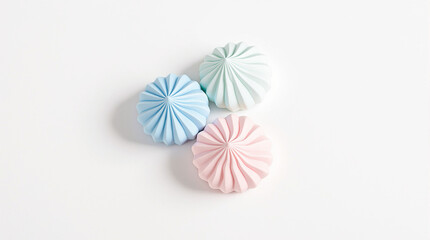 Three meringues of different colors on a white background