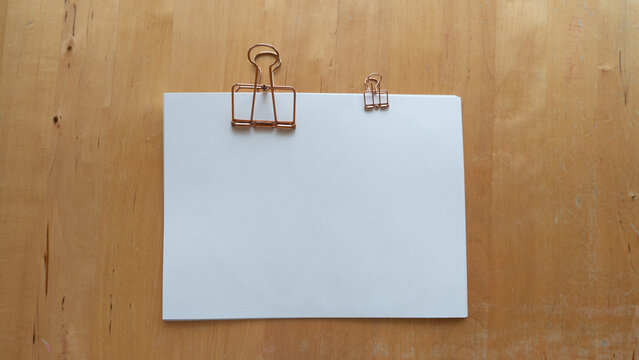 Blank White Message Card with Rose Gold Clips on the wooden table