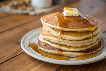 Pancake stack with syrup and butter melting on top captured with warm natural tones