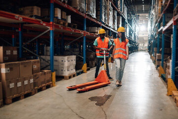 Warehouse workers transporting goods with pallet jack in distribution center