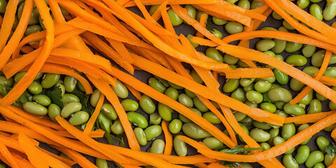 Carefully arranged julienned orange carrots lay in thin, elongated strips, creating a striking texture in contrast with the plump, smooth green edamame beans scattered Julienned Carrots and Edamame 