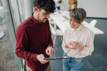 Business colleagues using digital tablet and drinking coffee in office