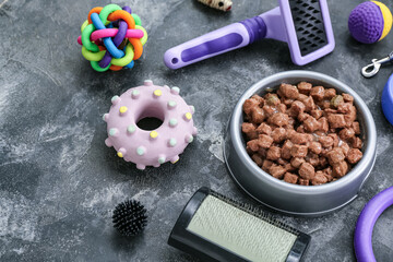 Composition with bowl of wet food and pet care accessories on grunge background