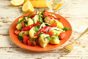Plate of tasty Potato Salad with vegetables on light wooden background