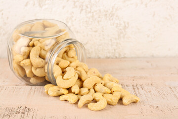 Jar with tasty cashew nuts on light background