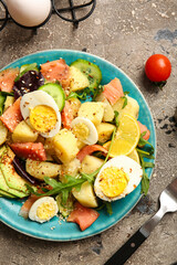 Plate of tasty potato salad with eggs and avocado on grey background, top view
