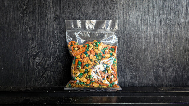 snack in clear plastic packaging on black background - Mixed peas snack (mixed peas) is a snack consisting of a mixture of various types of beans, including peas, sukro beans, koro beans,and pang-pang